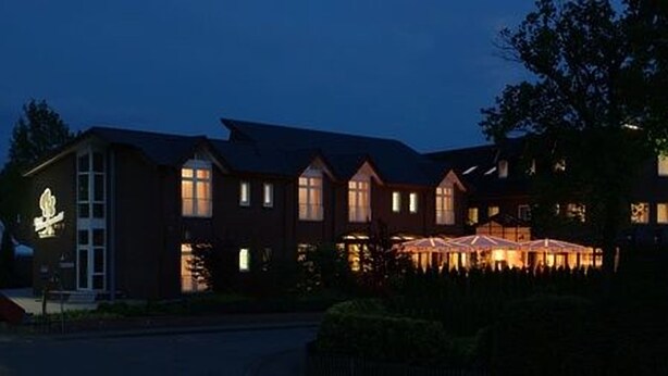 A large, multi-story building with a prominent entrance and a series of windows. - Hotel Zum Märchenwald (Lingen)