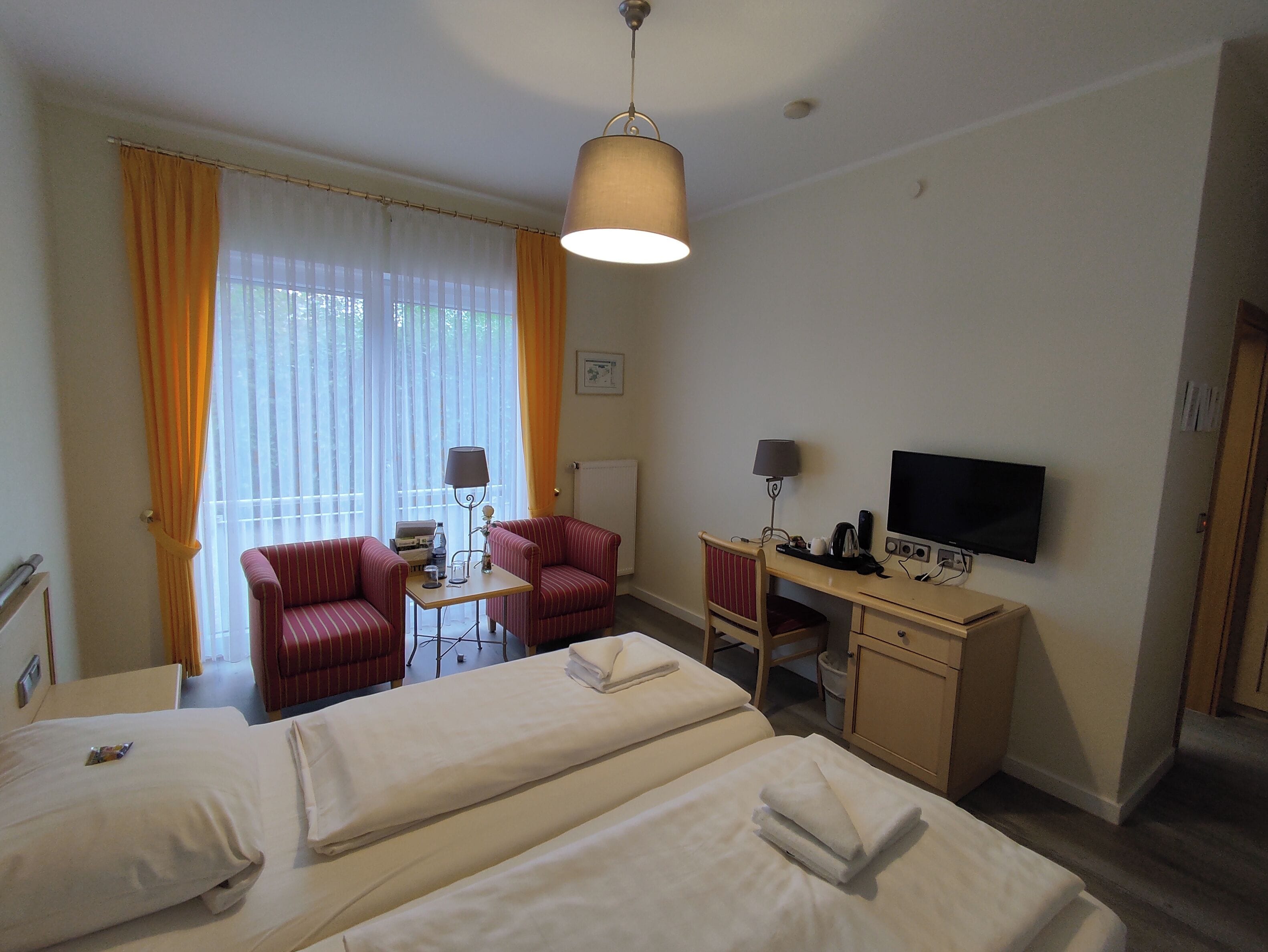 A hotel room with two beds, a desk, a television, and a chair.