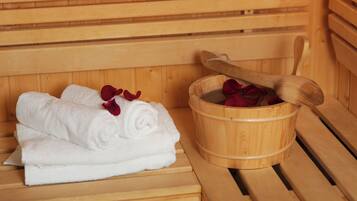Banca de sauna de madera con un cubo de madera que contiene un mortero de madera y pétalos de rosa roja.
