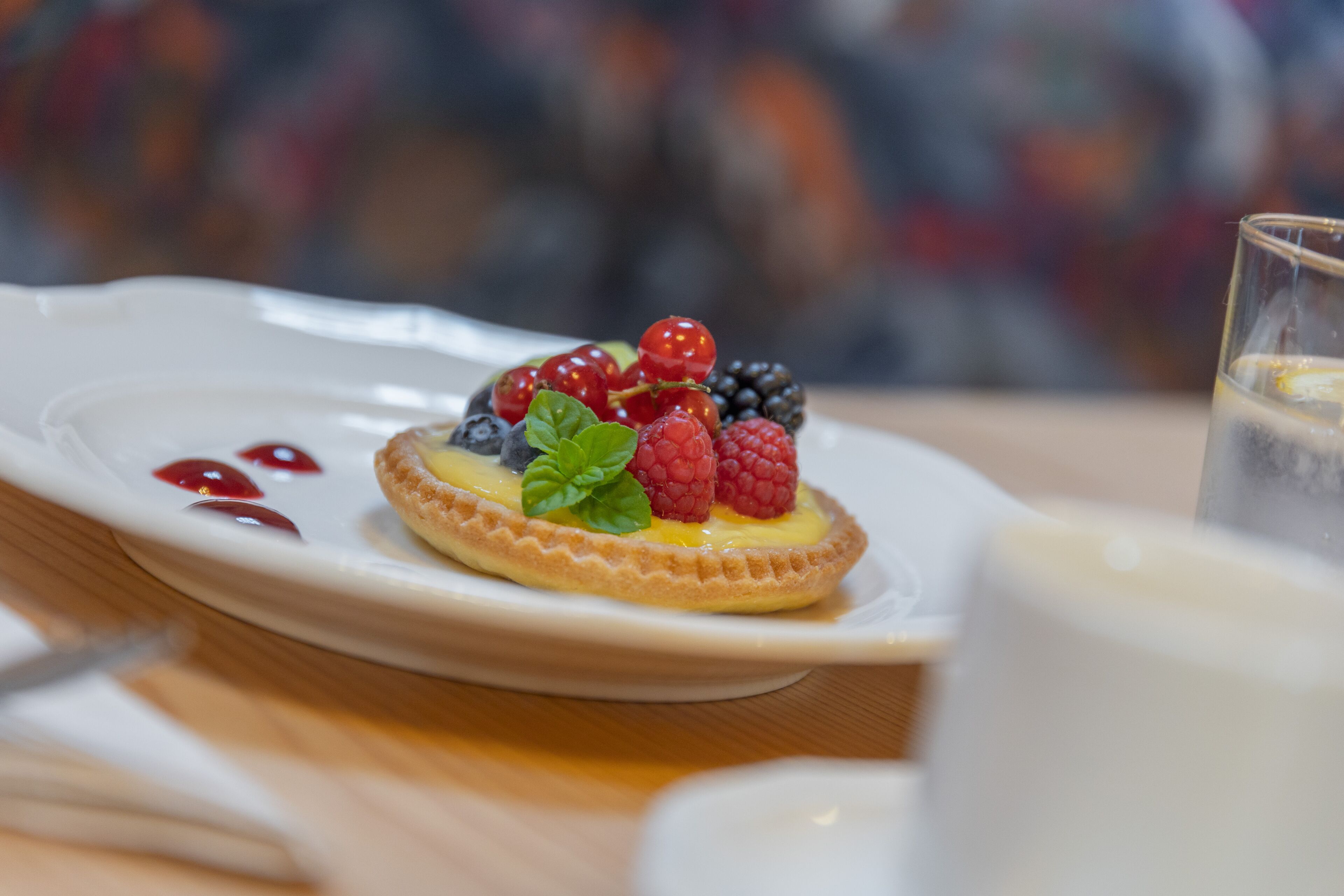 A dessert on a white plate with berries and mint leaves.