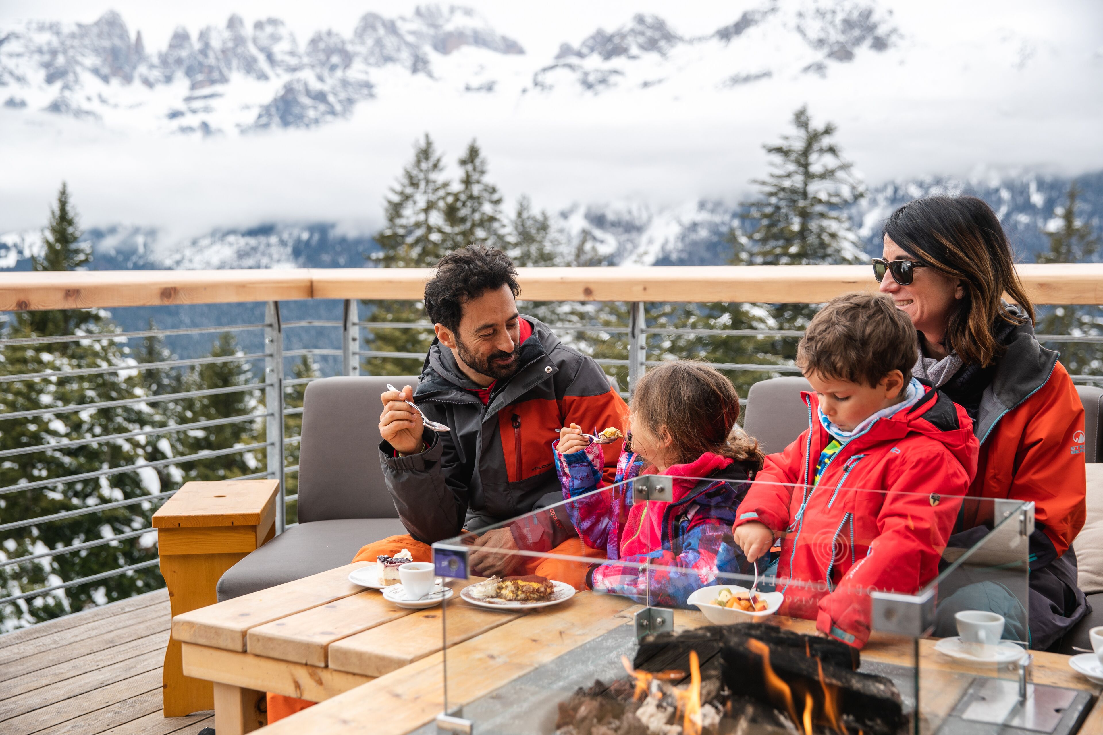 Una familia cenando al aire libre con vistas a la montaña.