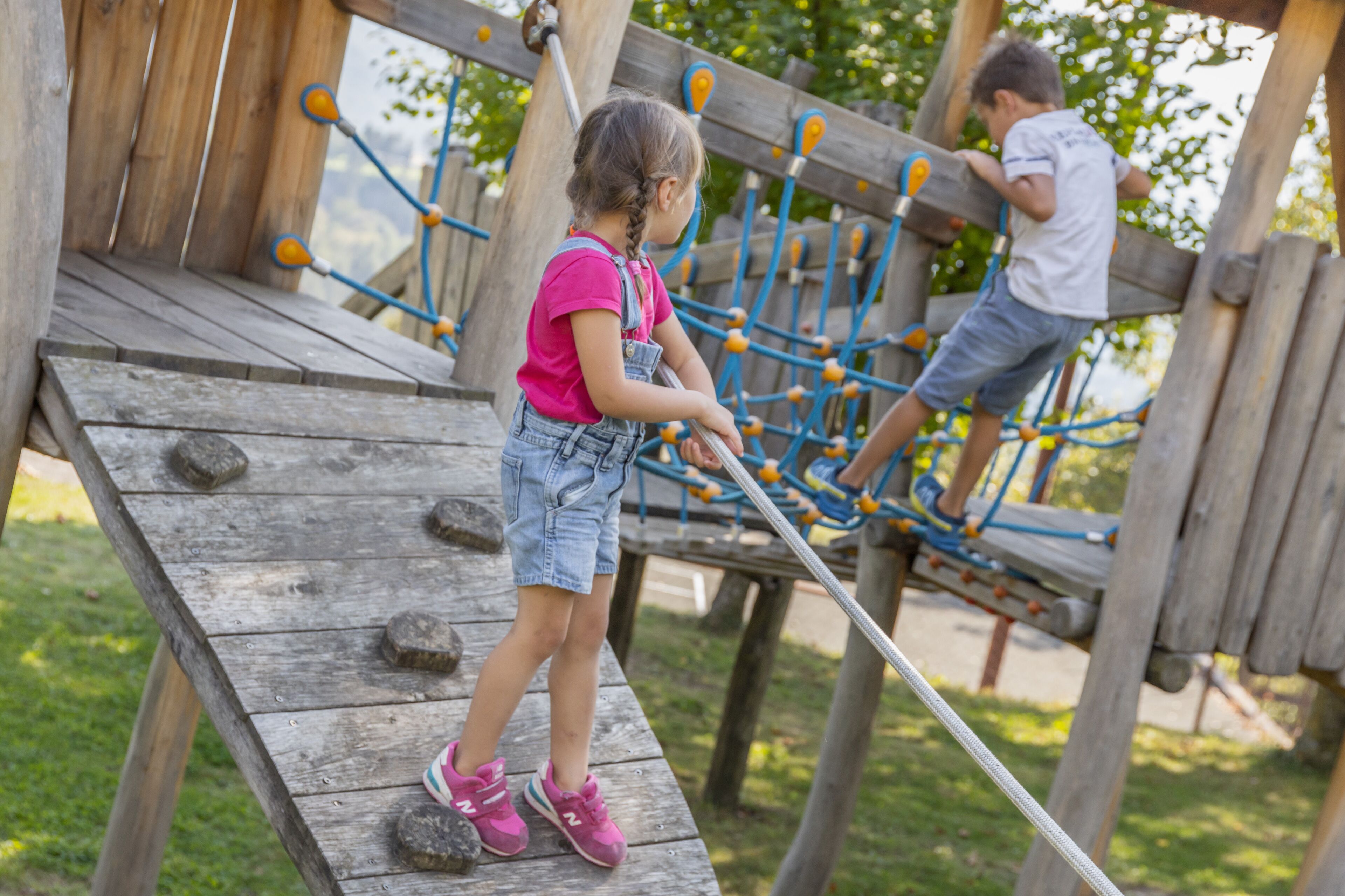 A wooden play structure with climbing elements and a flat platform.
