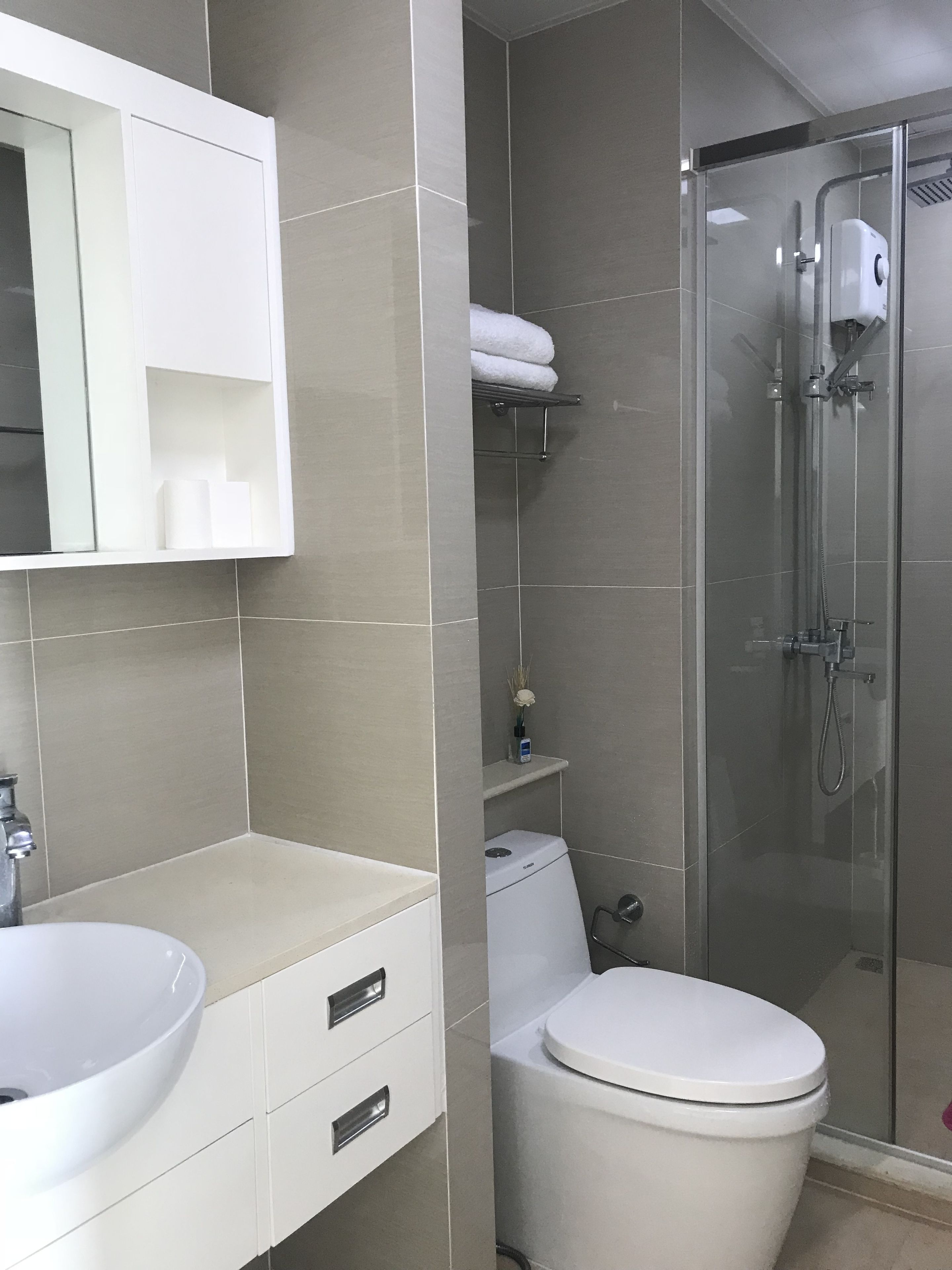 A bathroom with a white sink, a toilet, a glass-enclosed shower, and a mirror above the sink.
