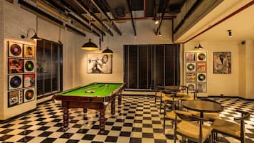 Una sala de billar con mesa de pool, suelo a cuadros y discos de vinilo en la pared.