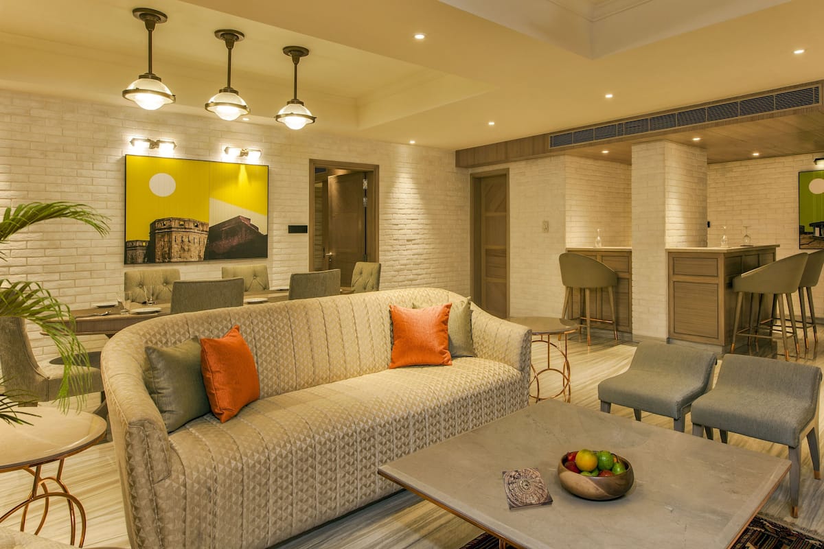 A modern living room with a sofa, chairs, a coffee table, and a dining area with a bar.