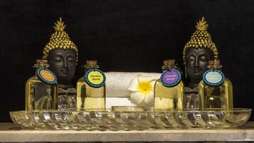 Una exhibición de cuatro estatuas de Buda con botellas etiquetadas de aceites esenciales frente a ellas.