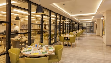 Un comedor moderno con mesas redondas, sillas verdes e iluminación colgante.