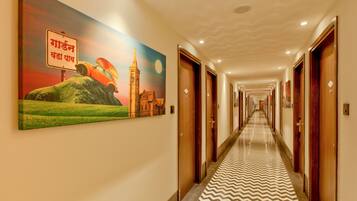 A hotel hallway with a long corridor, wooden doors, and a patterned floor.