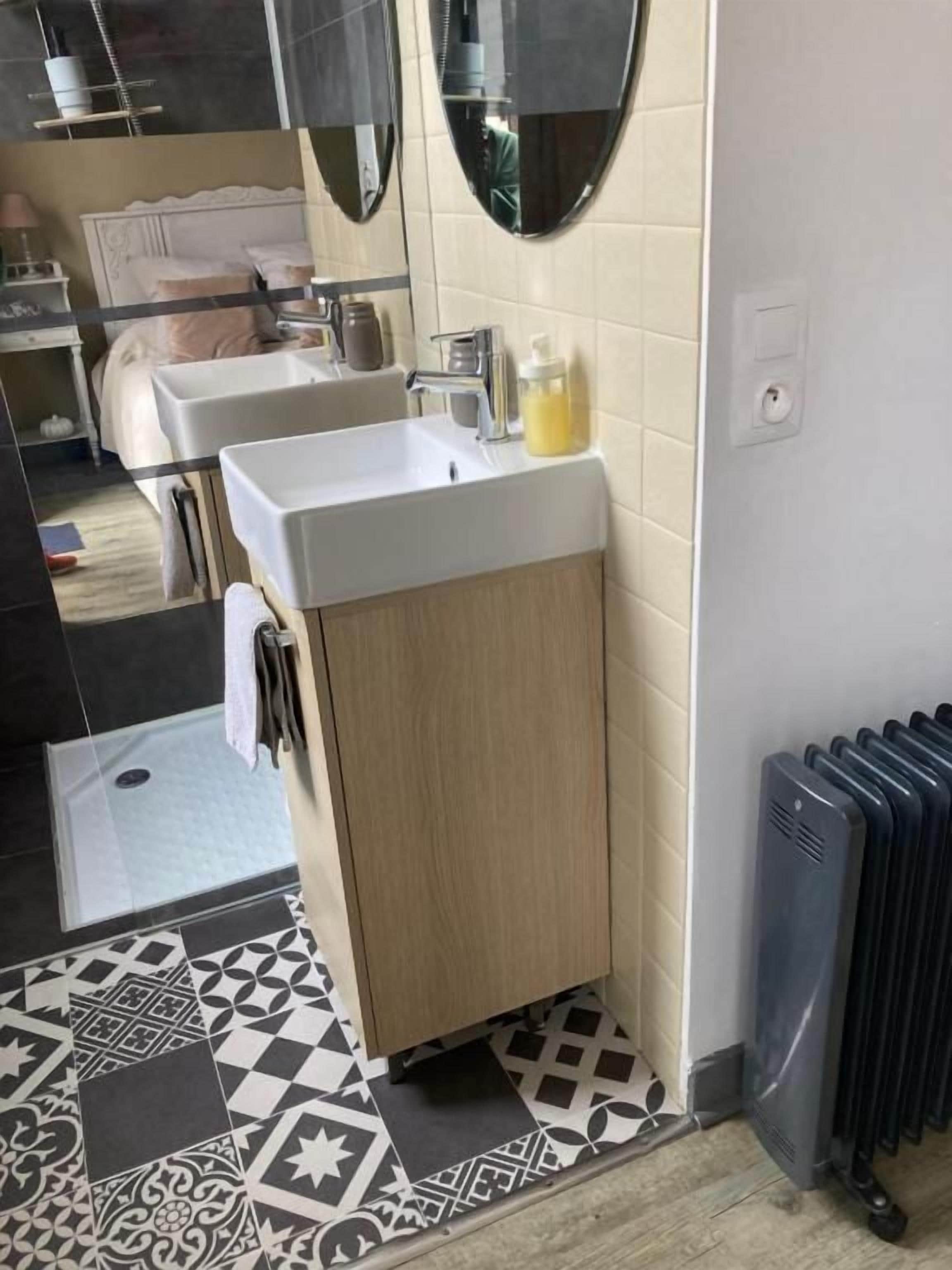 A bathroom with a sink, mirror, and radiator.