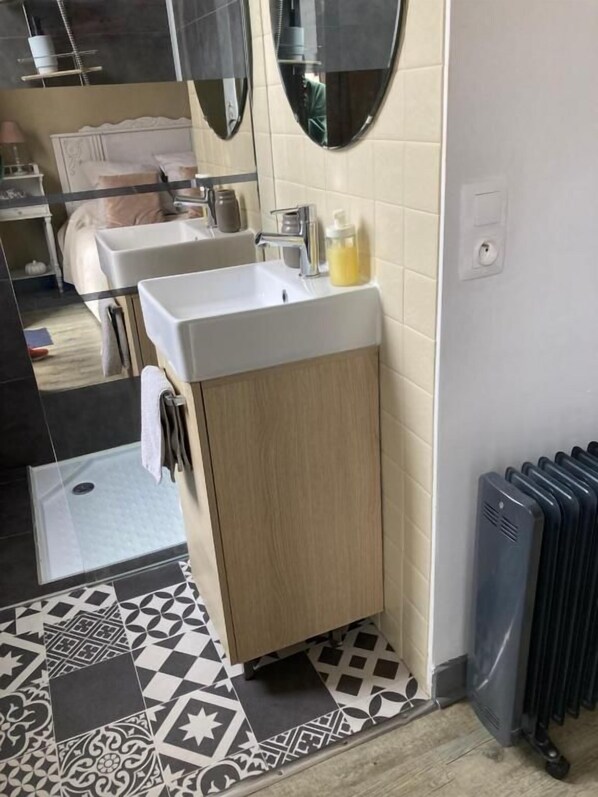 A bathroom with a sink, mirror, and radiator.