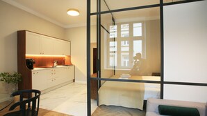 A modern hotel room with a glass partition, a kitchenette, a bed, and a seating area. - Faust and Mona Lisa Apartments (Kraków)