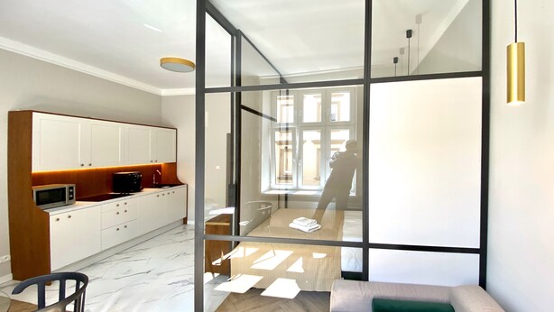 A modern kitchen with white cabinets, a microwave, and a wooden countertop. - Faust and Mona Lisa Apartments (Kraków)