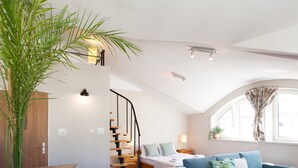 A modern bedroom with a curved ceiling, a staircase, a bed, a sofa, and a large plant. - Faust and Mona Lisa Apartments (Kraków)