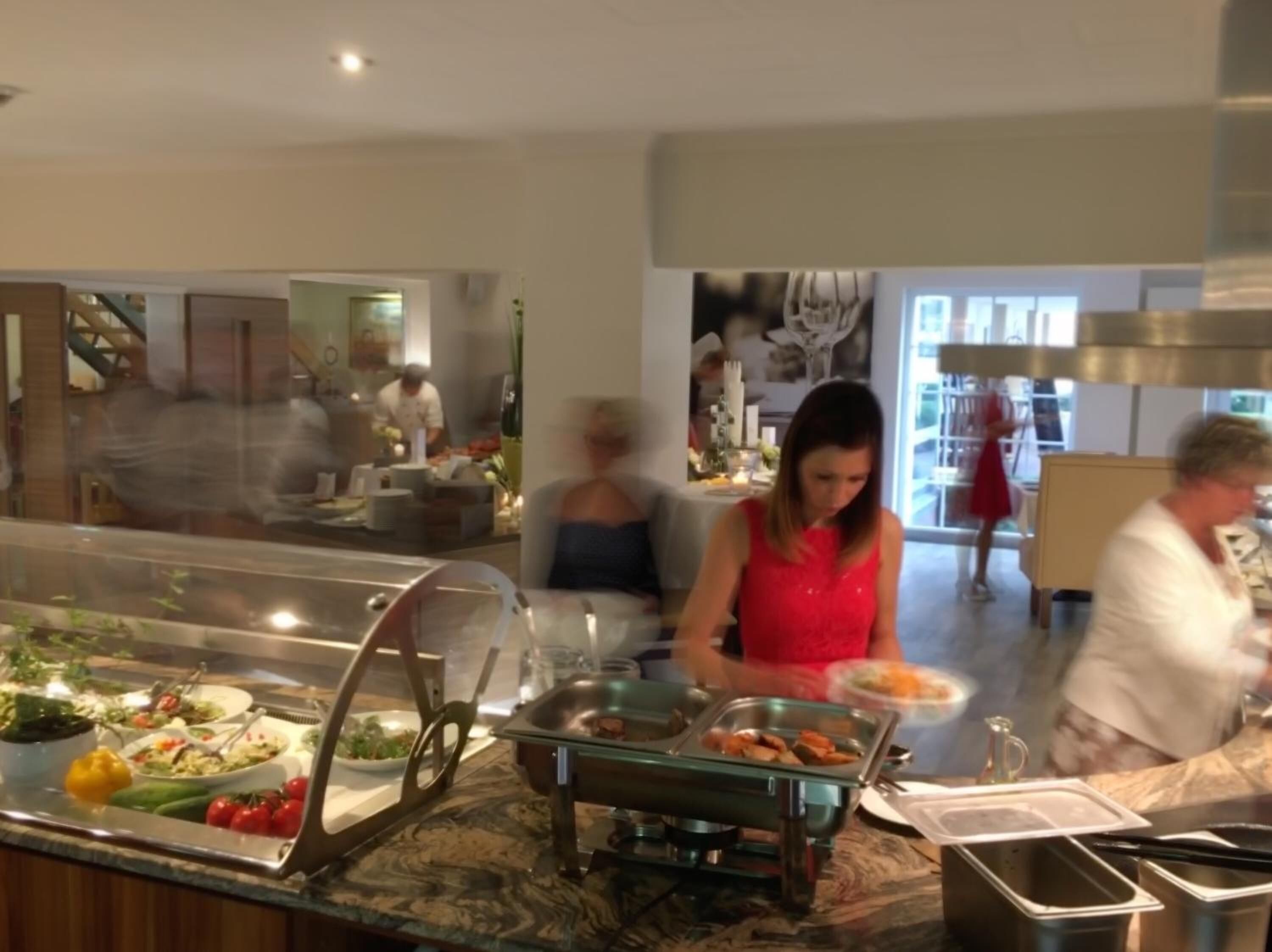 A buffet area with various food options, a glass display case, and a counter with a sink.