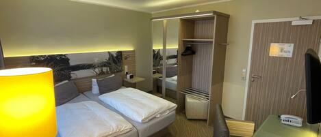 A hotel room with a bed, bedside table, lamp, and a mirror.