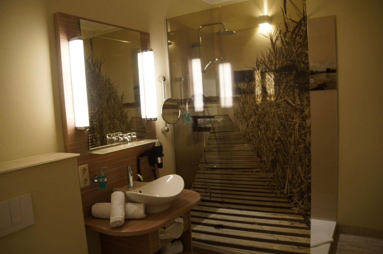 A modern bathroom with a large mirror, a sink, and a shower.