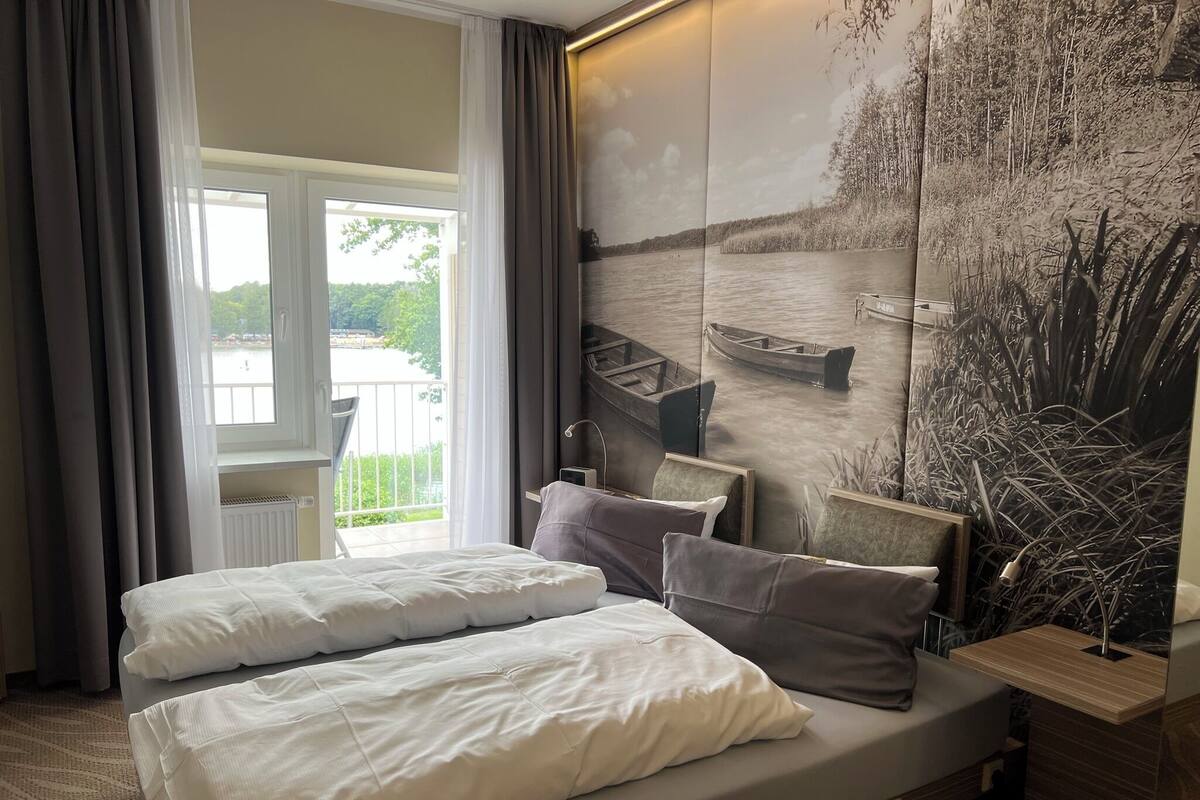 Ein Hotelzimmer mit Bett, Blick auf Boote auf dem Wasser und einem großen Fenster.