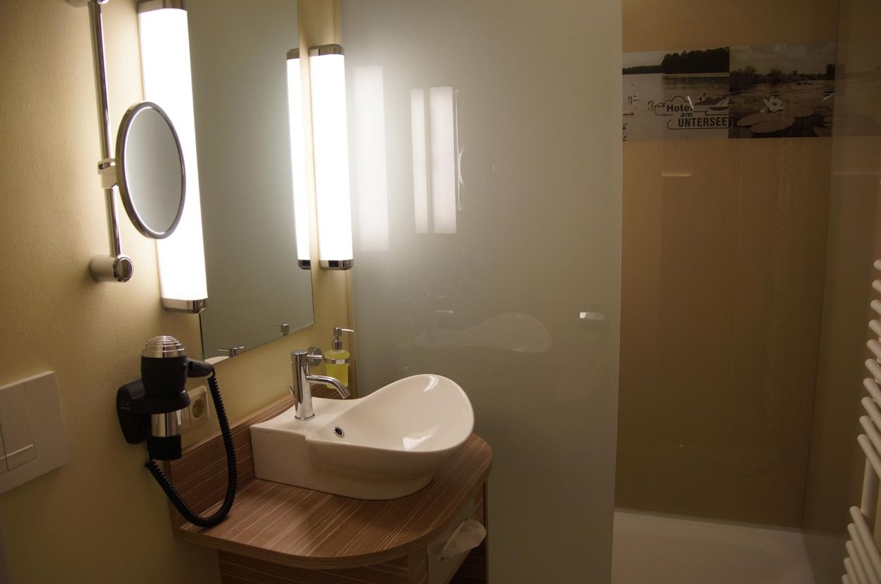 Un baño con lavamanos, espejo y secador de pelo.