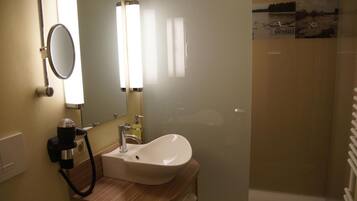Un baño con lavamanos, espejo y secador de pelo.