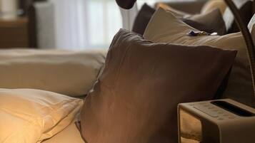 A neatly made bed with a bedside table, a lamp, and a radio.