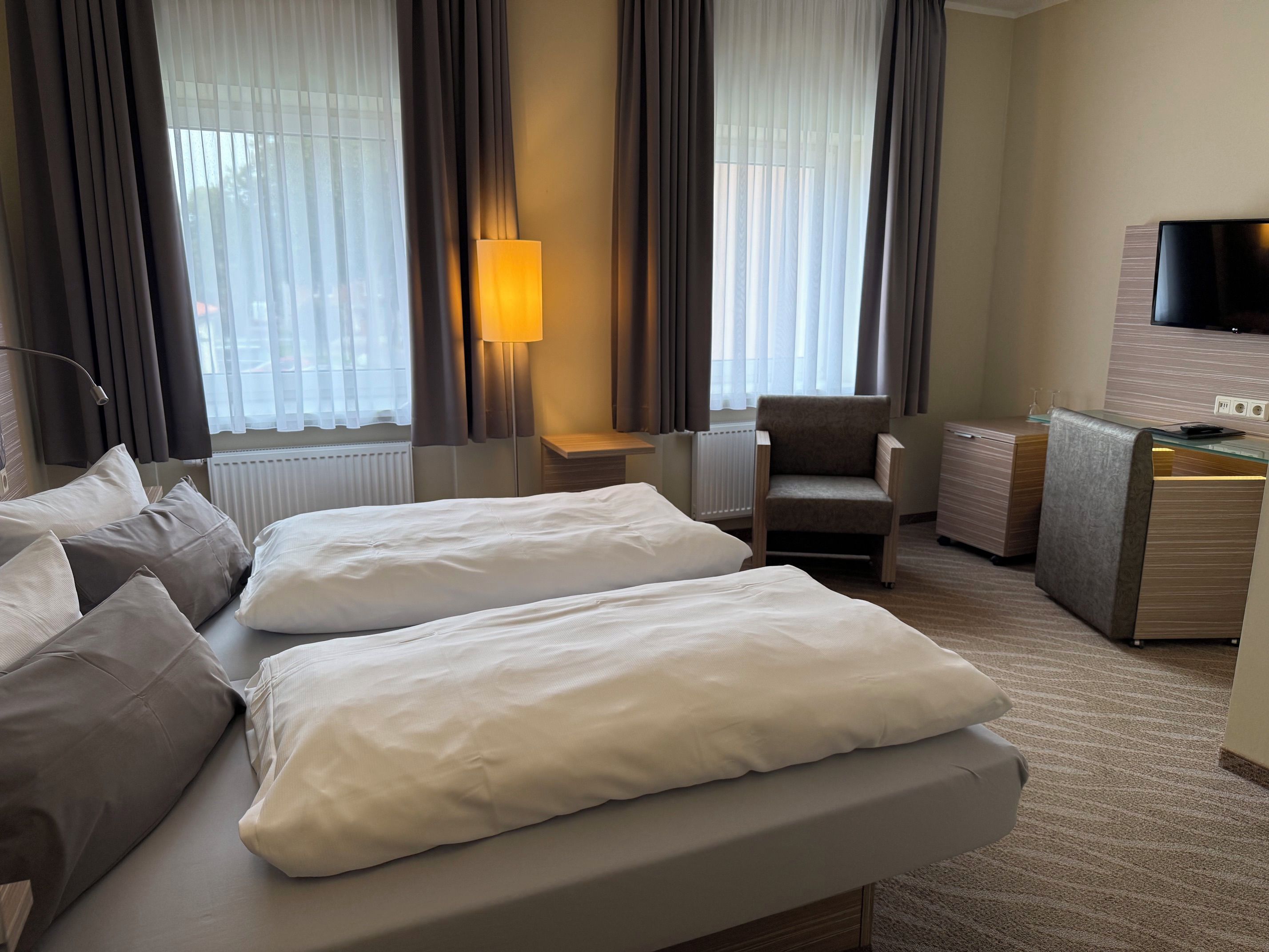 Hotellihuone, jossa on sänky, tuoli, työpöytä ja televisio.