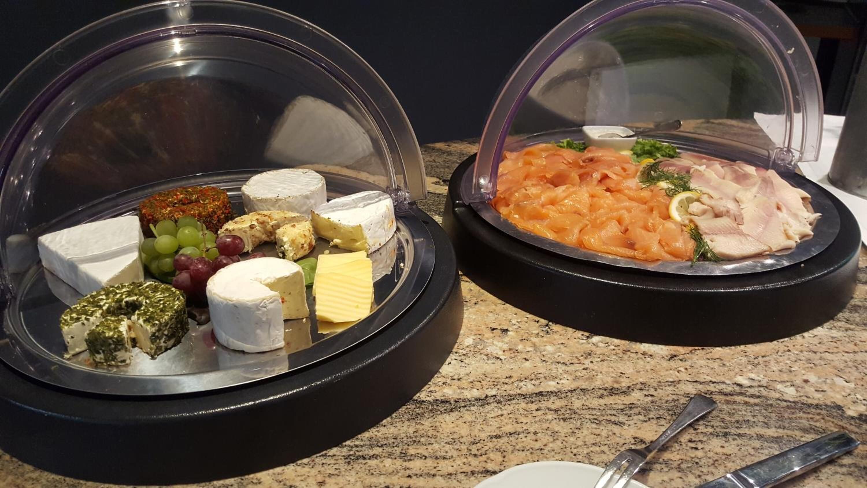 Dos mostradores cubiertos con varios quesos, uvas y salmón ahumado.