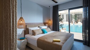 Ein modernes Hotelzimmer mit einem großen Bett, zwei Nachttischen, Blick auf einen Swimmingpool und einem Balkon mit Gartenmöbeln.
