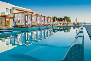 Área de piscina com várias espreguiçadeiras e uma cobertura.