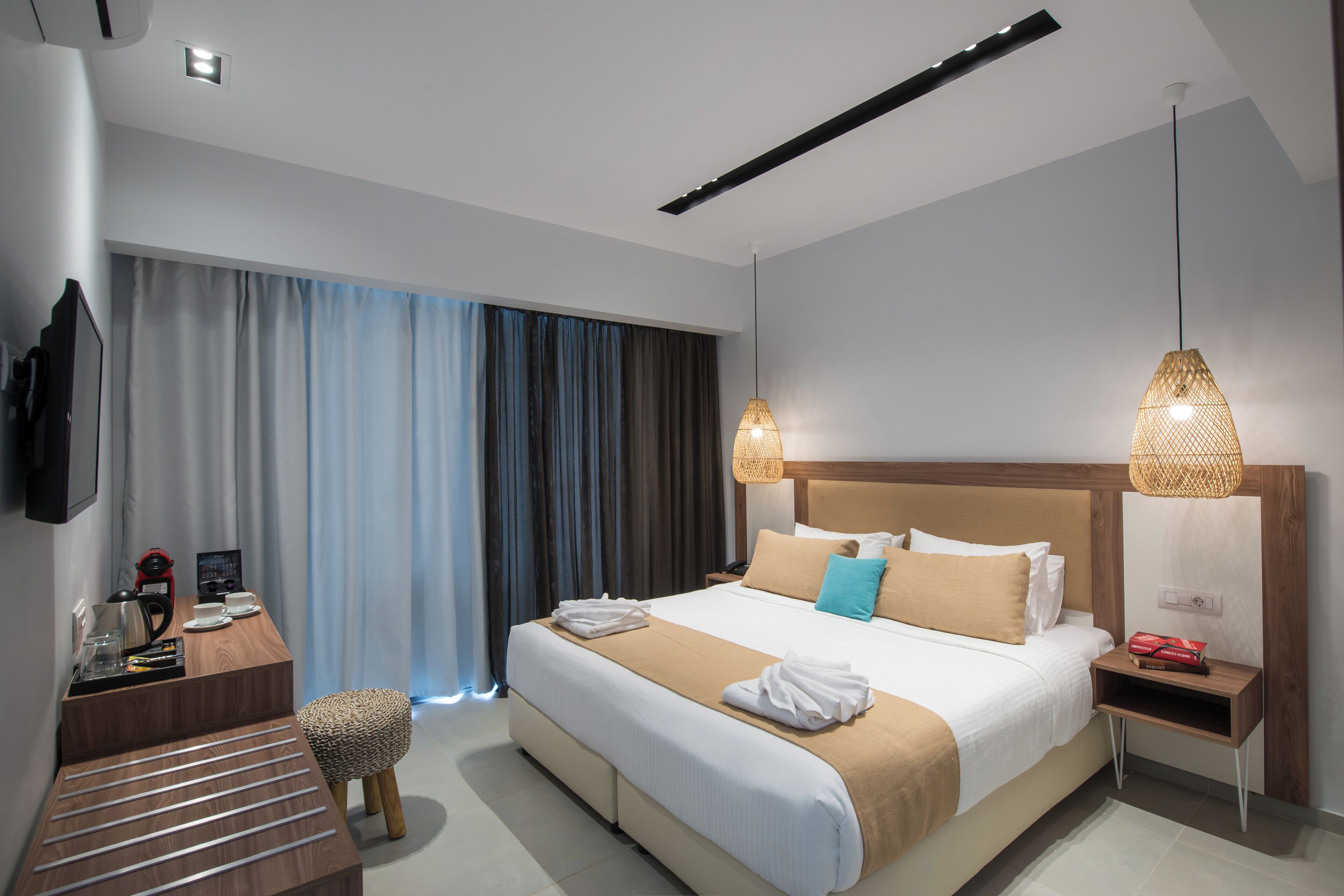 A modern hotel room with a large bed, bedside tables, a desk, and a television.