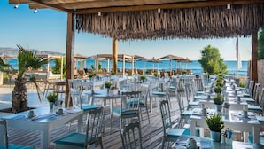 Ein Restaurant am Strand mit Terrassensitzgelegenheiten, Tischen, Stühlen und Sonnenschirmen.