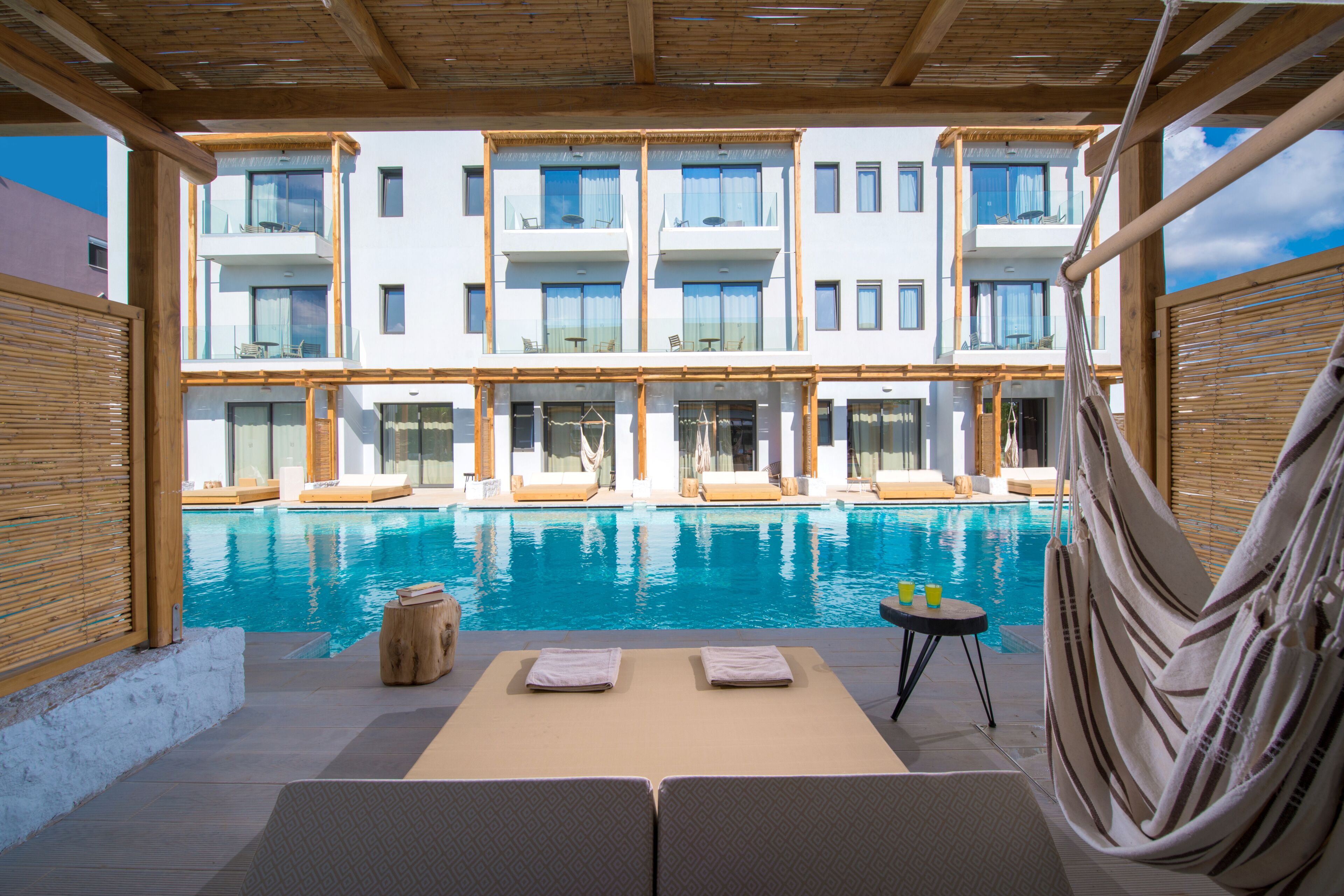A modern hotel with a pool, lounge chairs, and a view of the building.