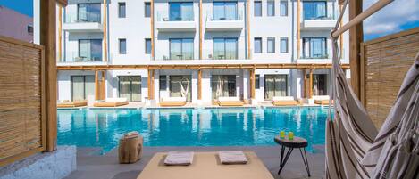 A modern hotel with a pool, lounge chairs, and a view of the building.