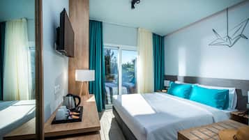 Una habitación de hotel moderna con una cama grande, un escritorio de madera, un televisor de pantalla plana y vistas al exterior.
