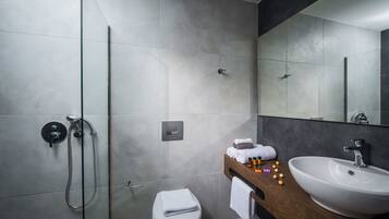 A modern bathroom with a glass shower enclosure, a white toilet, and a wooden vanity with a sink and mirror.