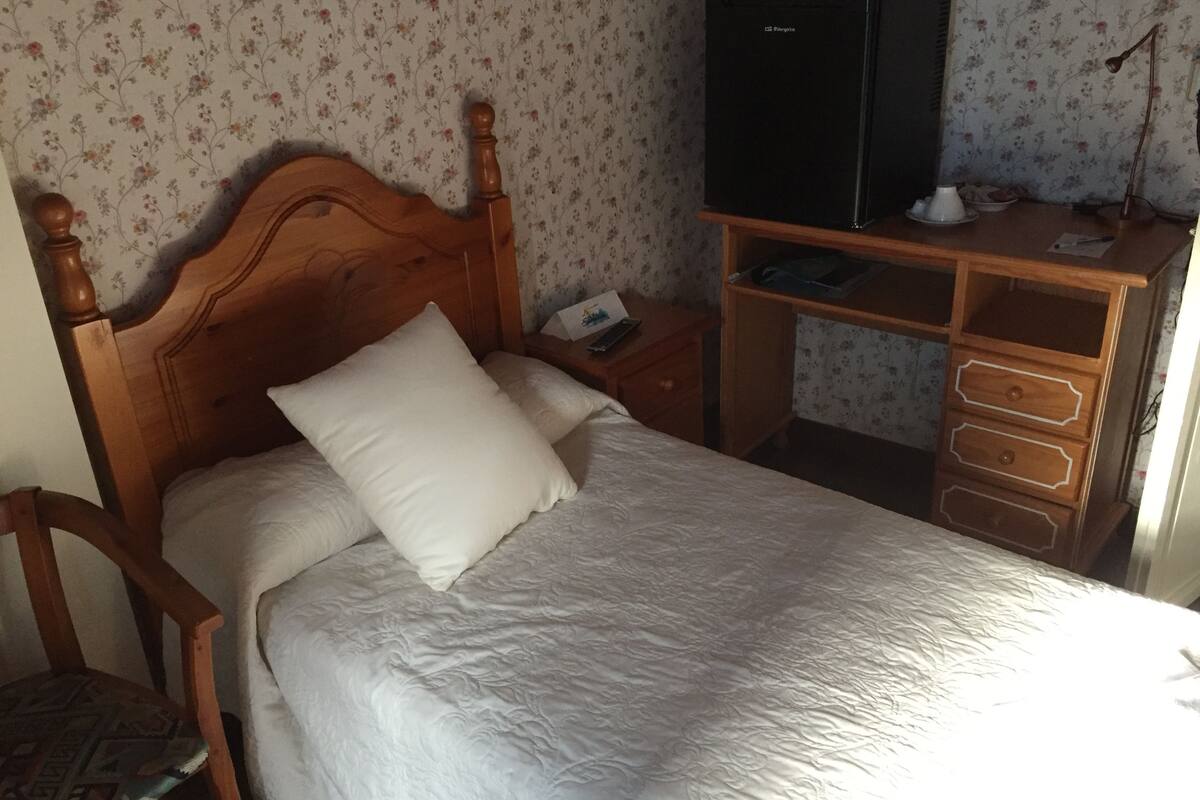 Un dormitorio con una cama de madera, una mesita de noche, un aparador y un televisor sobre un mueble.