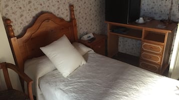 Un dormitorio con una cama de madera, una mesita de noche, un aparador y un televisor sobre un mueble.