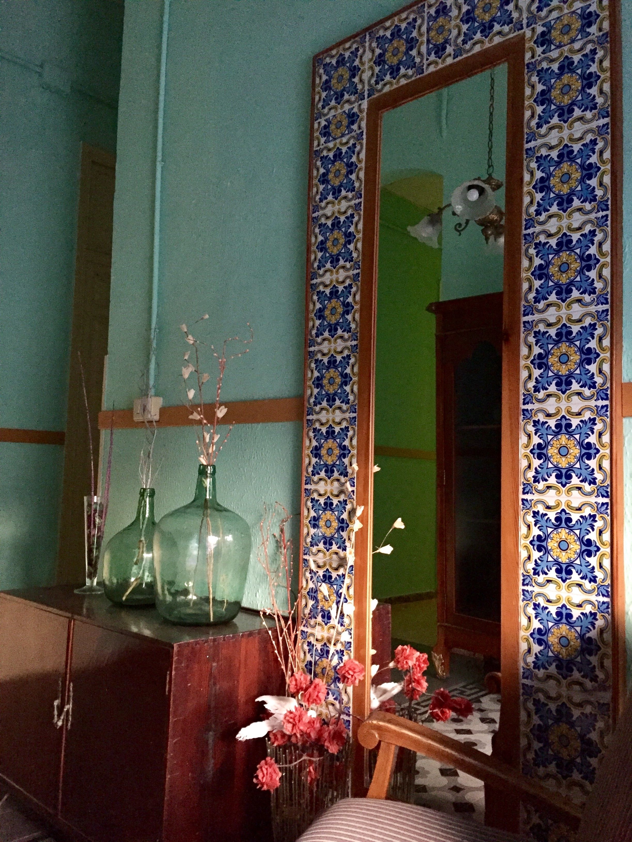 Una habitación con un espejo grande, un armario de madera y un muro con azulejos.
