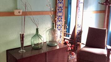 A room with a wooden cabinet, a chair, and a mirror with a blue and white tile border.