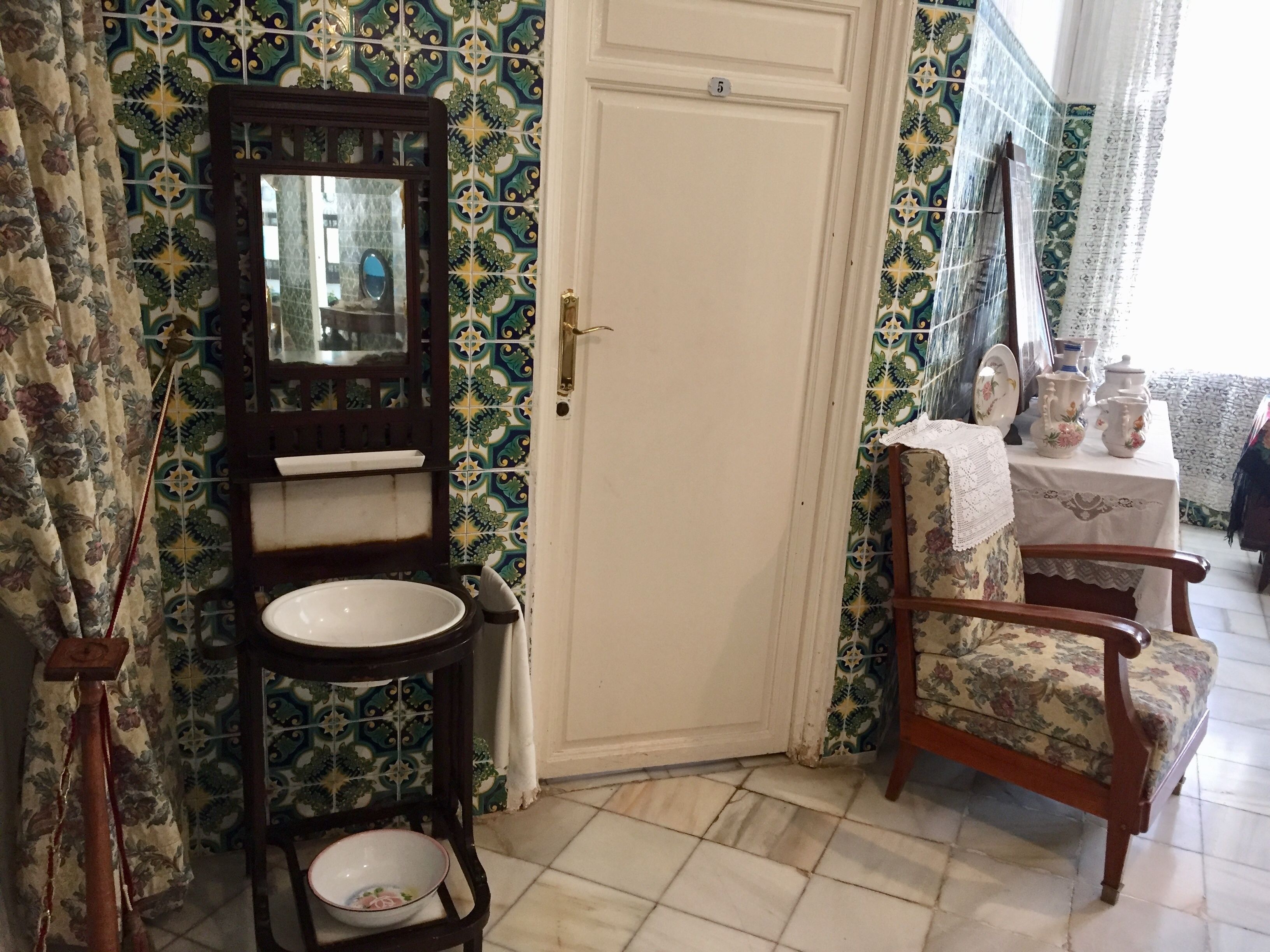A bathroom with a sink, mirror, and a door with a number.