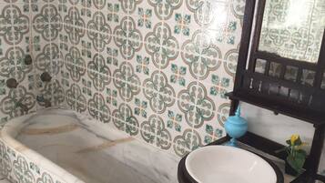 Un baño con bañera, lavabo, espejo y una pequeña planta en maceta.