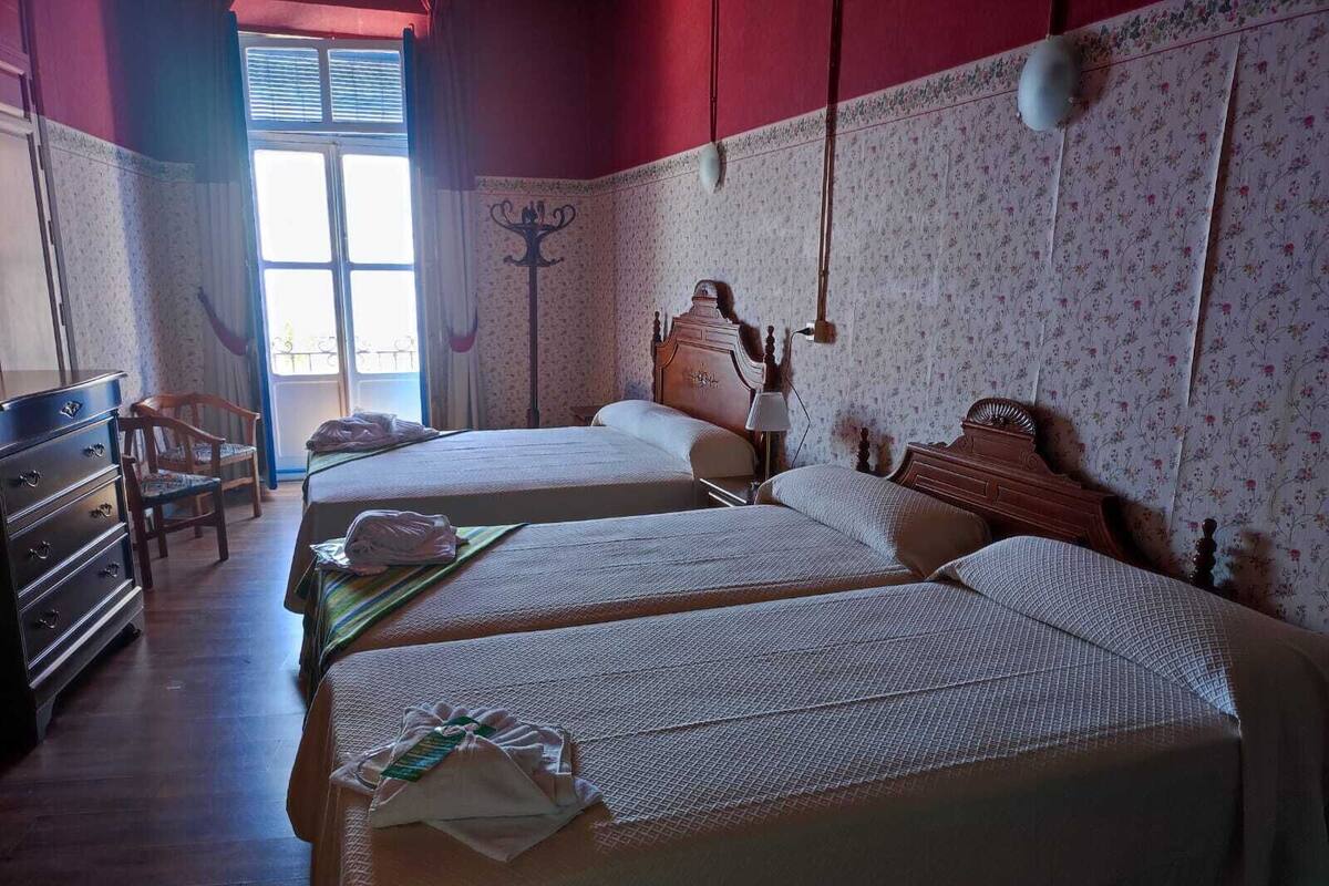 Una habitación con dos camas, un aparador de madera y una silla.