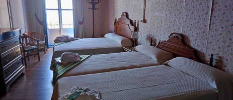 A room with two beds, a wooden dresser, and a chair.
