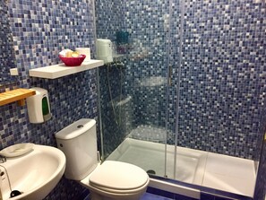Un baño con inodoro, bidé y cabina de ducha con mampara de vidrio.