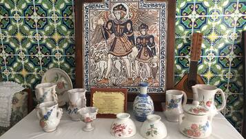 Una mesa con varios objetos de cerámica, una obra de arte enmarco y una placa.