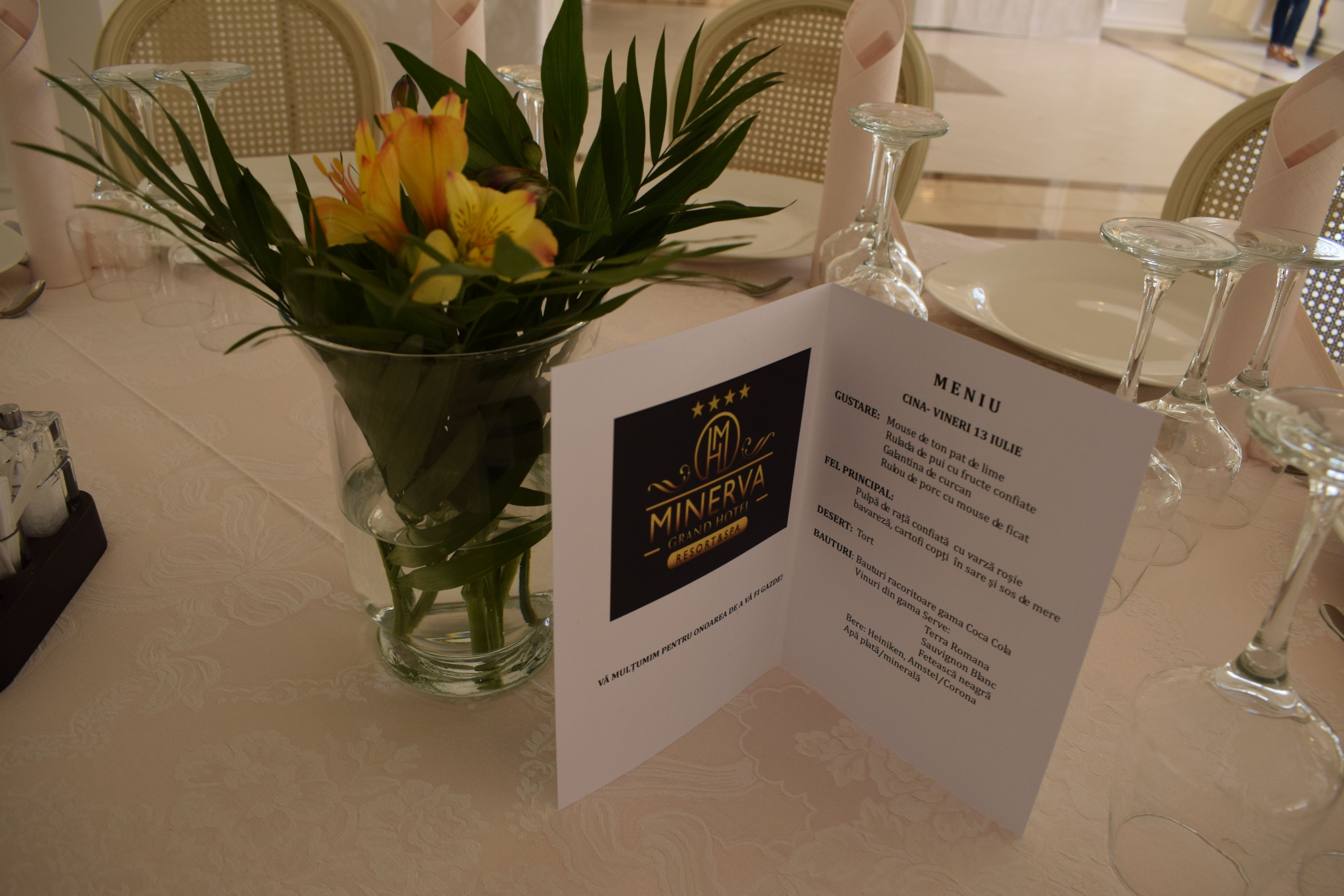 Un menú sobre una mesa de restaurante con un florero de flores.