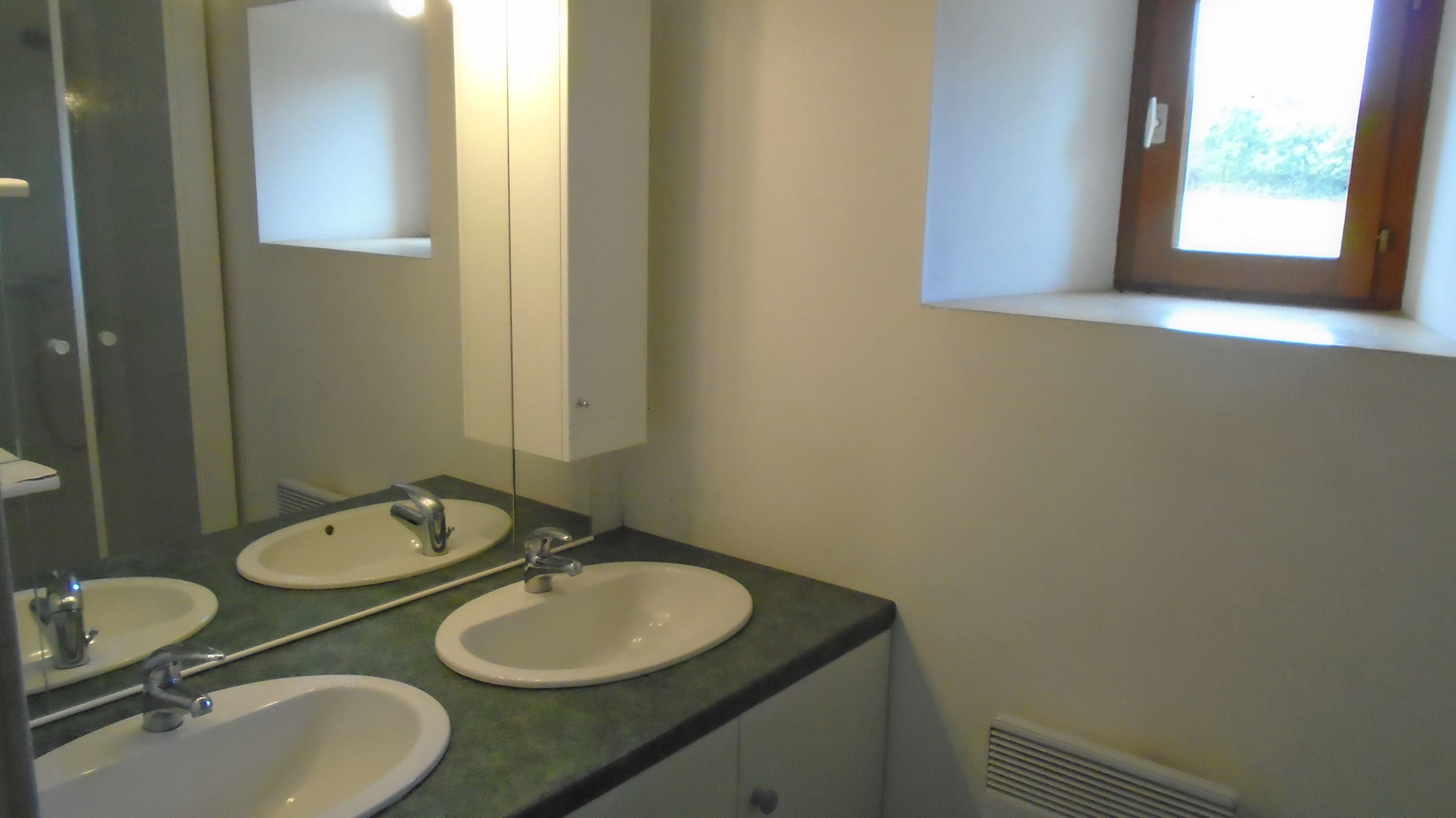 A bathroom with two sinks, a mirror, and a window.