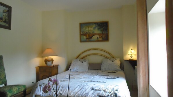 A bedroom with a bed, two bedside lamps, a nightstand, a chair, and a painting on the wall. - Logis le Manoir de la Foulerie (Saint-Sauveur-Villages)