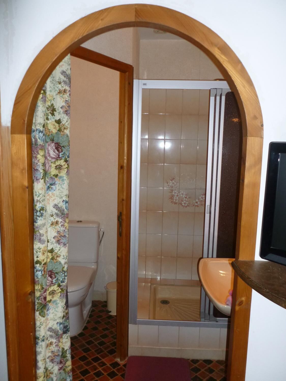 Een badkamer met een douche, toilet en een deurkozijn van hout.
