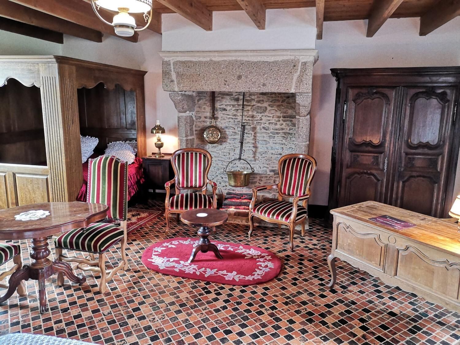 A cozy room with a stone fireplace, wooden furniture, and a tiled floor.
