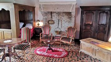 A cozy room with a stone fireplace, wooden furniture, and a tiled floor.